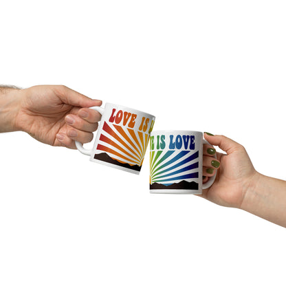 Mano sujetando taza de cerámica con mensaje Love Is Love y diseño de rayos arcoíris retro.